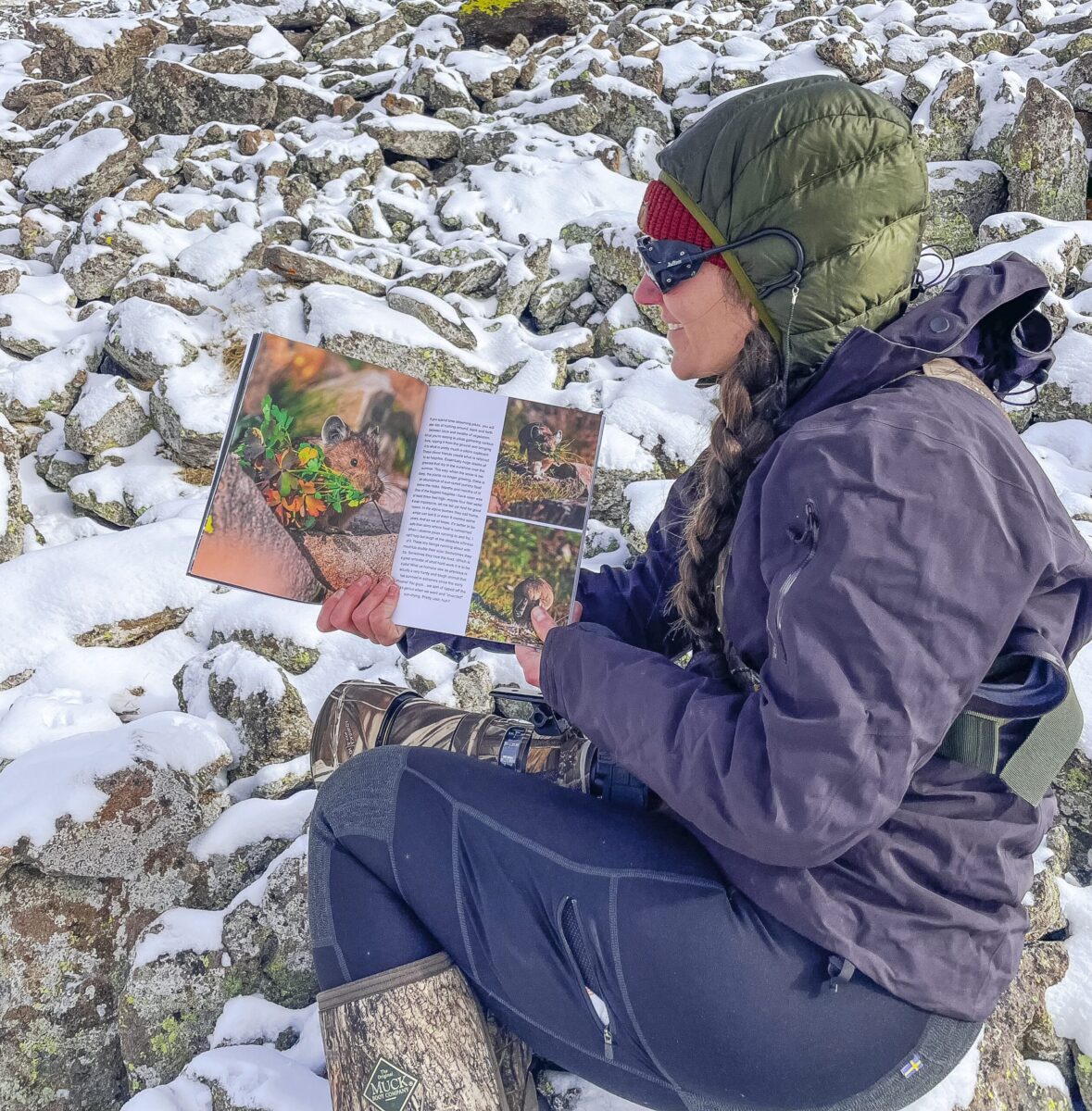 A woman reads a book about pikas in a talus field