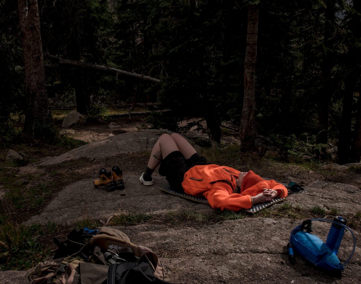 A backpacker snoozes out in the open on a rock